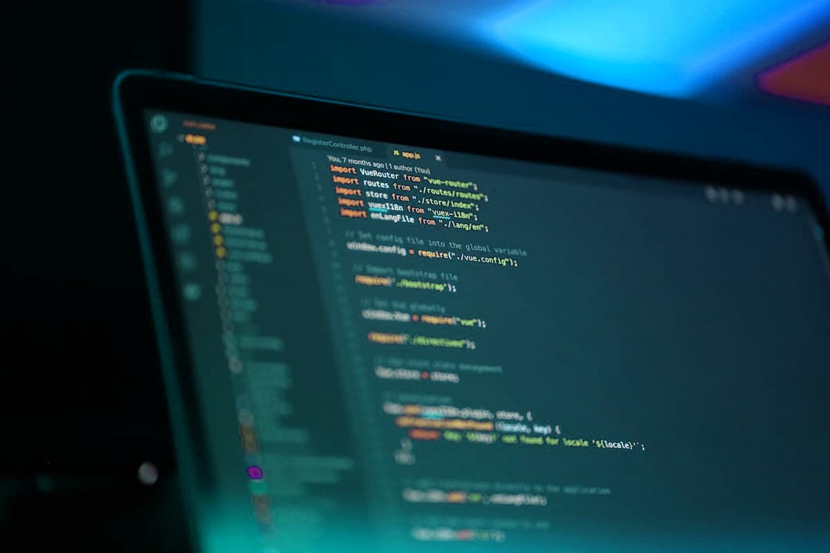 Code on a laptop screen lit in teal and blue